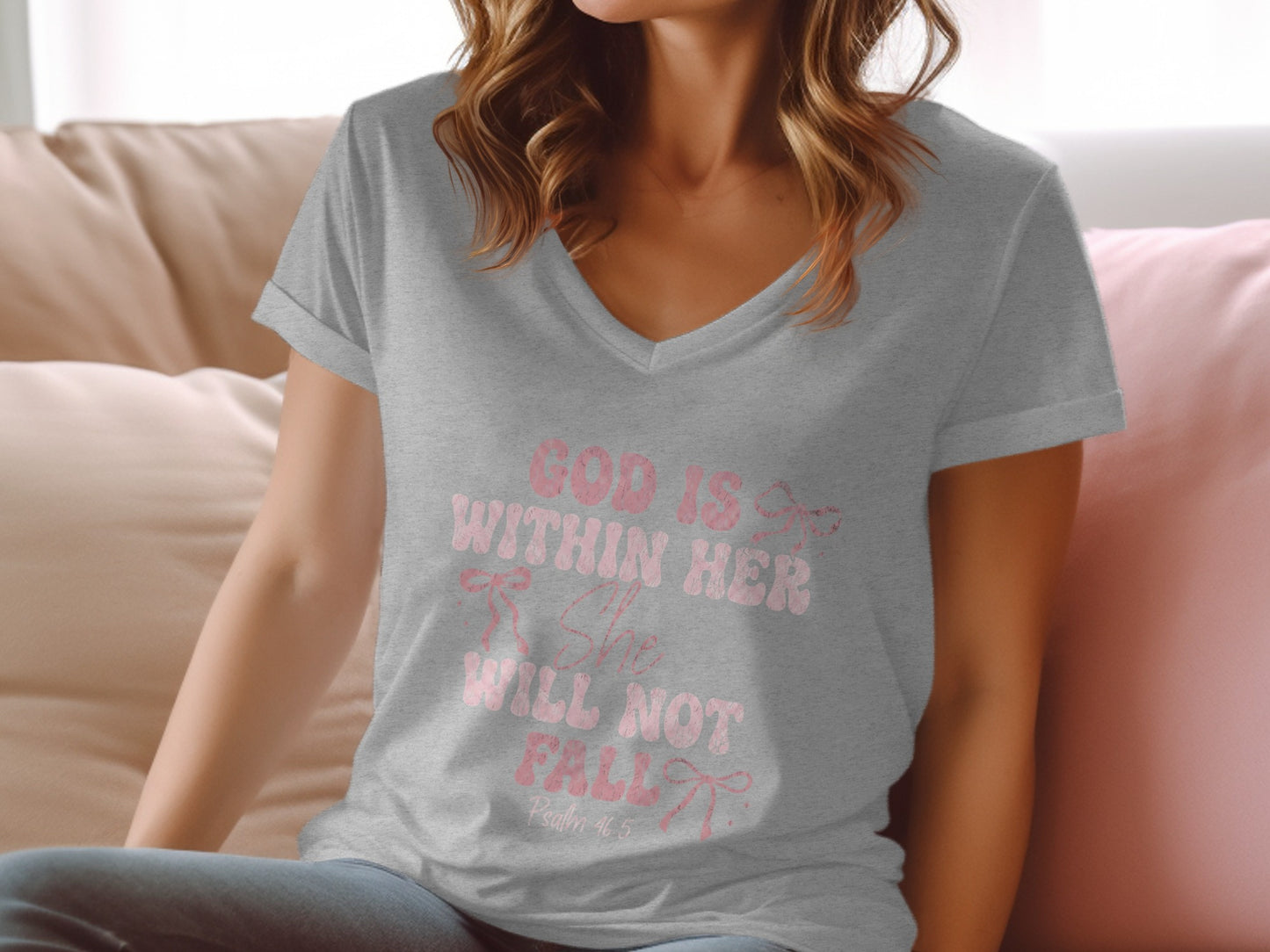 Woman wearing a grey t-shirt with "God is her strength, she will not fall" text.