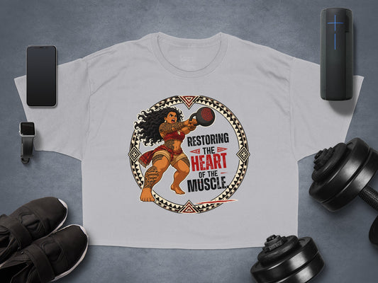 T-shirt with graphic of a muscular woman lifting a kettlebell, text "Restoring the heart of the muscle".