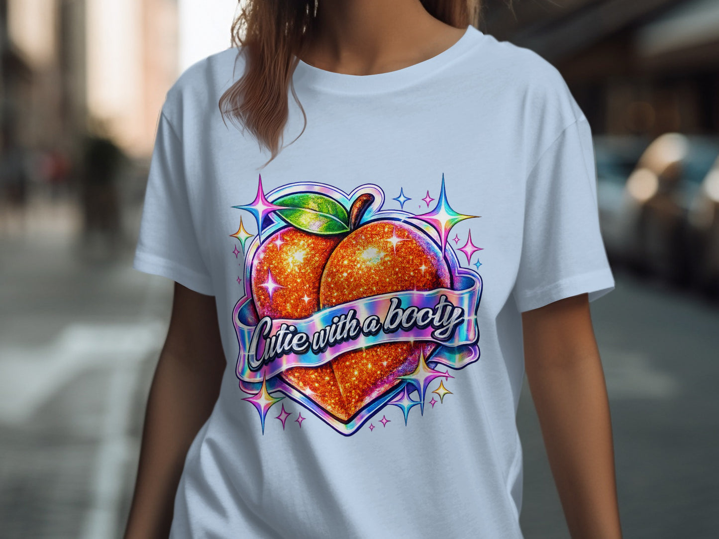 Glittery peach graphic with "Cutie with a booty" text on white t-shirt.