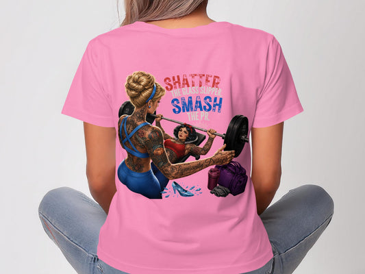 Woman in pink t-shirt with tattoos lifting weights, "Shatter The Glass Slipper Smash The Pic" text.