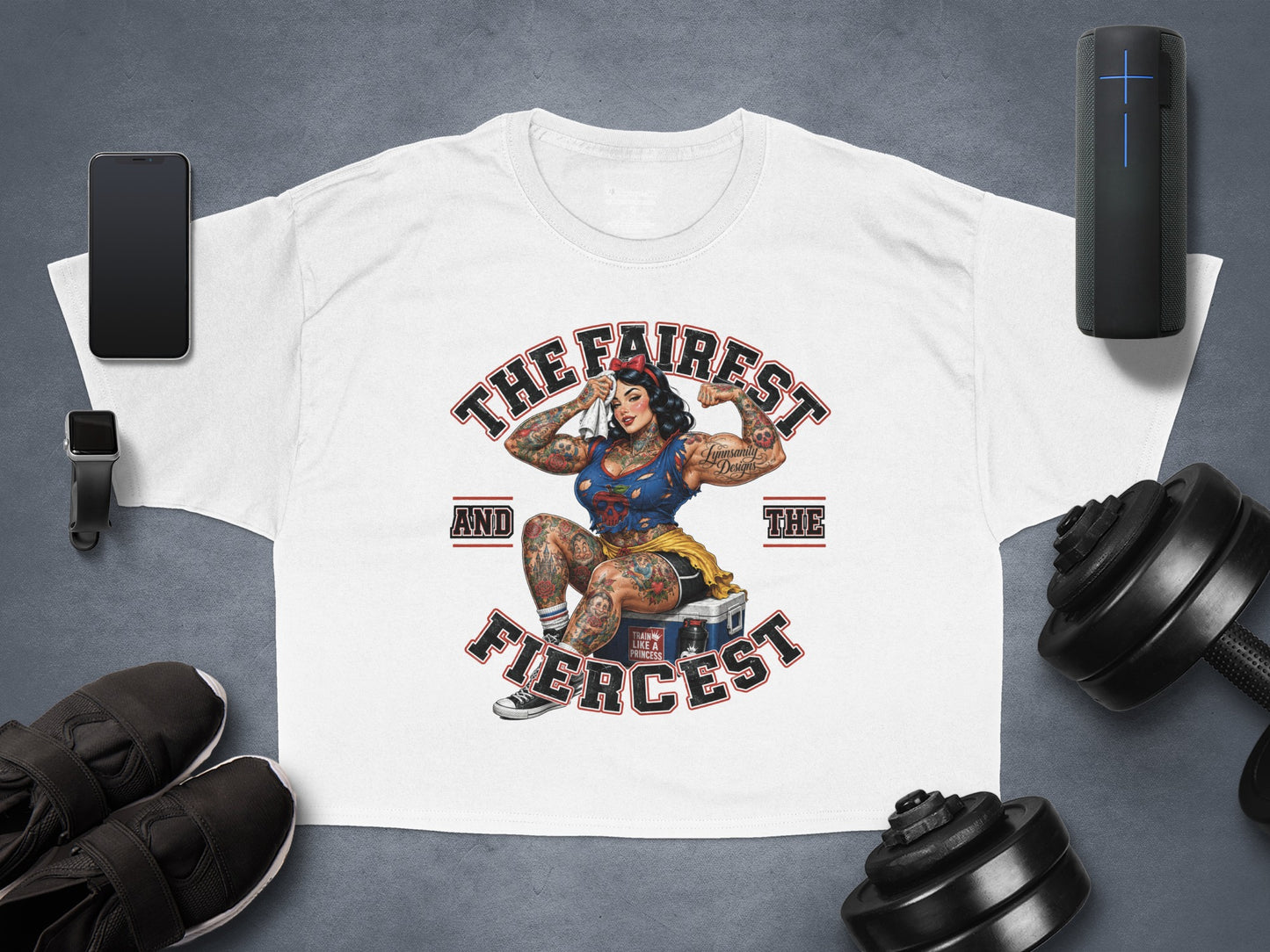 White t-shirt with a graphic of a tattooed woman flexing, text reads "THE FAIREST AND THE FIERCEST".