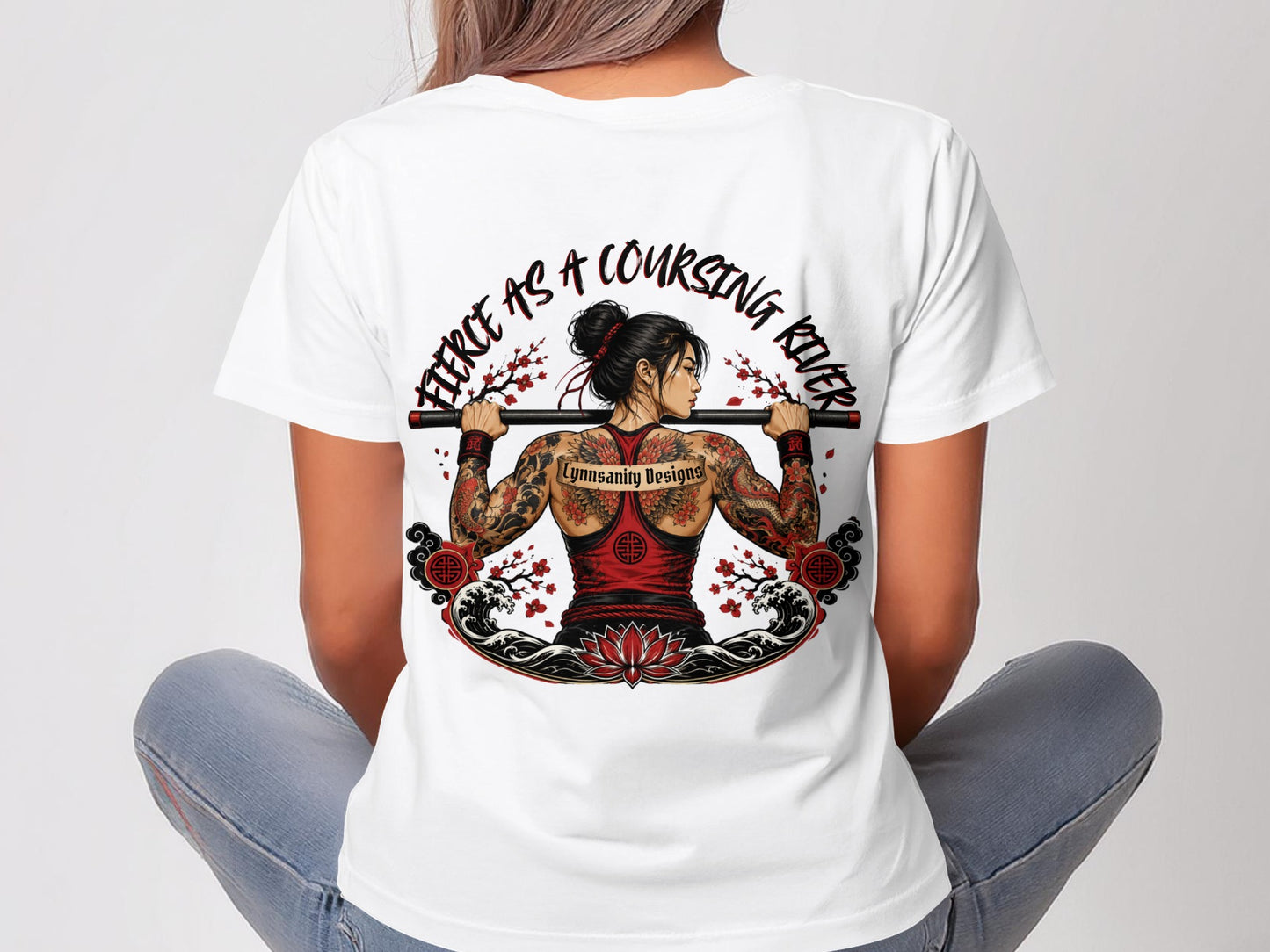Woman wearing a white t-shirt with a large back graphic of a tattooed woman lifting a bar.