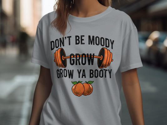 White t-shirt with "Don't Be Moody Grow Ya Booty" text and barbell graphic.