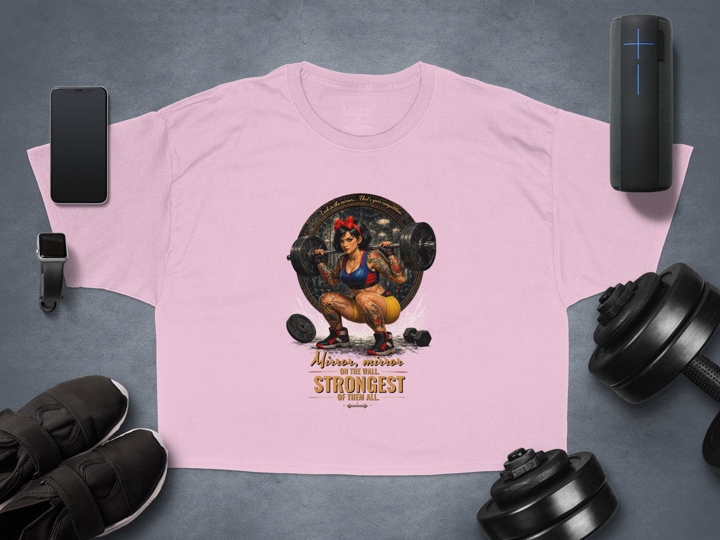 Pink crop top with tattooed woman lifting weights graphic and inspirational text.