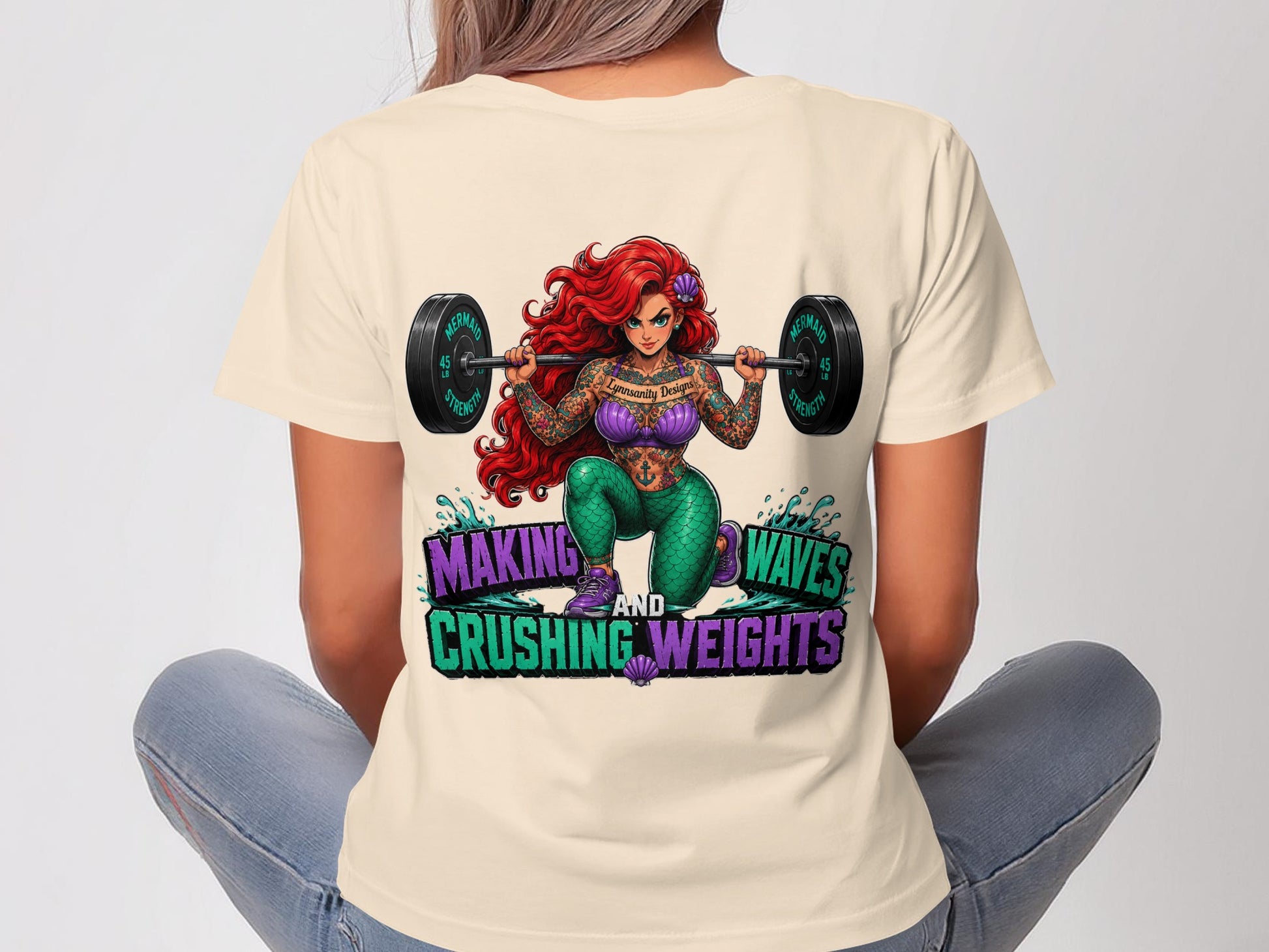Ariel tattooed and lifting weights with inspirational text.