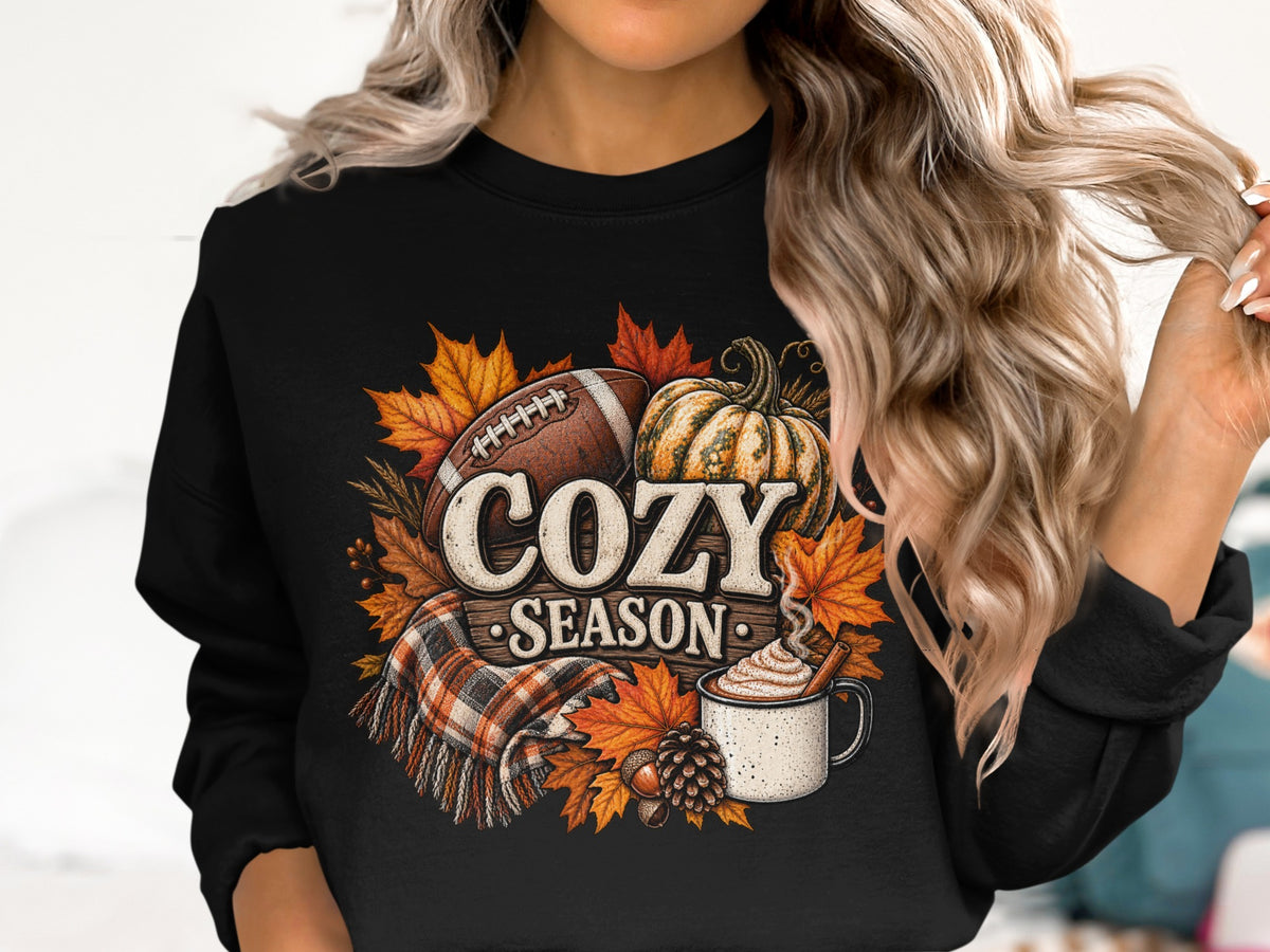 Crewneck sweatshirt with "Cozy Season" text, football, pumpkin, and autumn leaves.