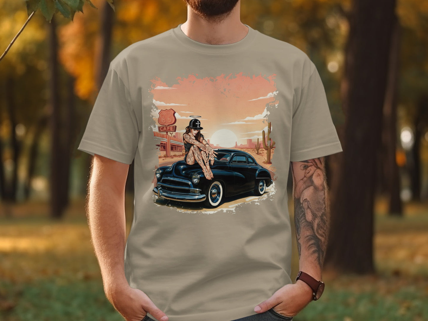 T-shirt featuring tattooed woman on classic car, Route 66 sign, sunset.