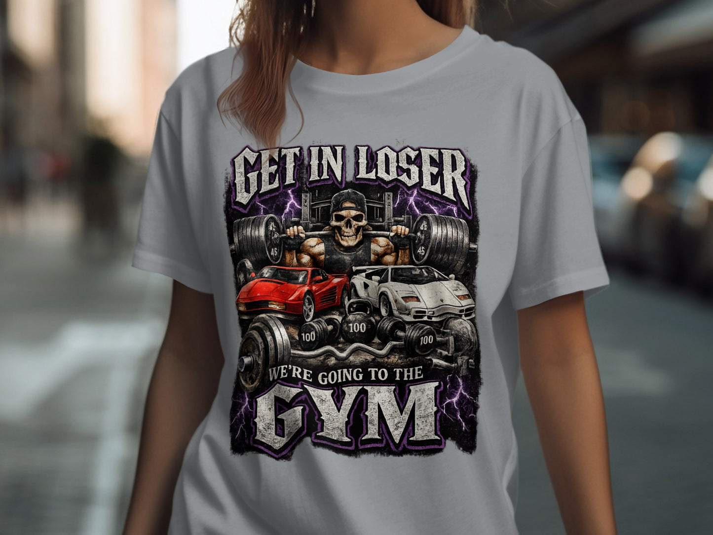 Graphic t-shirt with skull, weights, cars, and text "GET IN LOSER WE'RE GOING TO THE GYM".