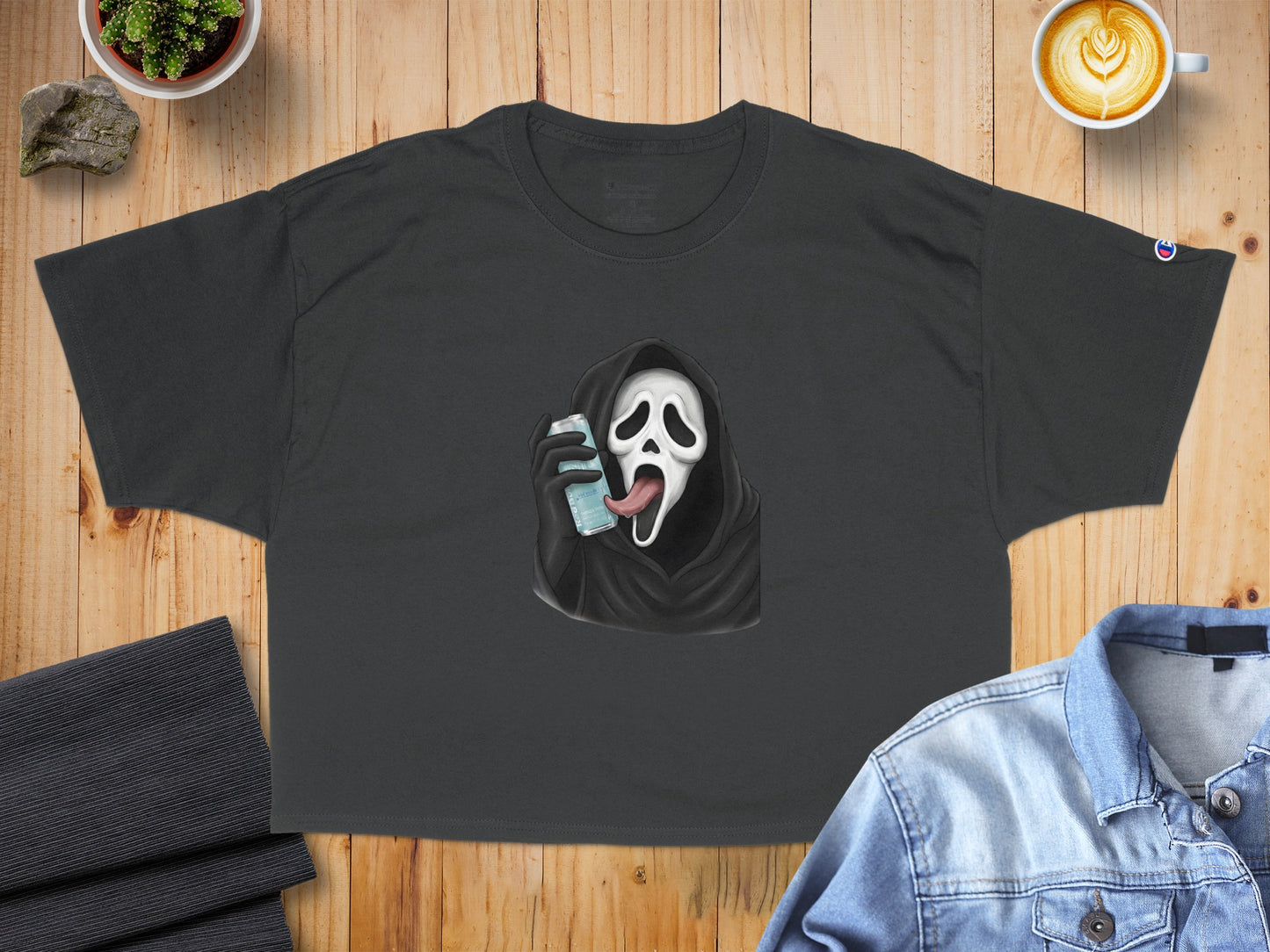 Dark t-shirt with Ghostface from Scream holding a can of soda with tongue out.