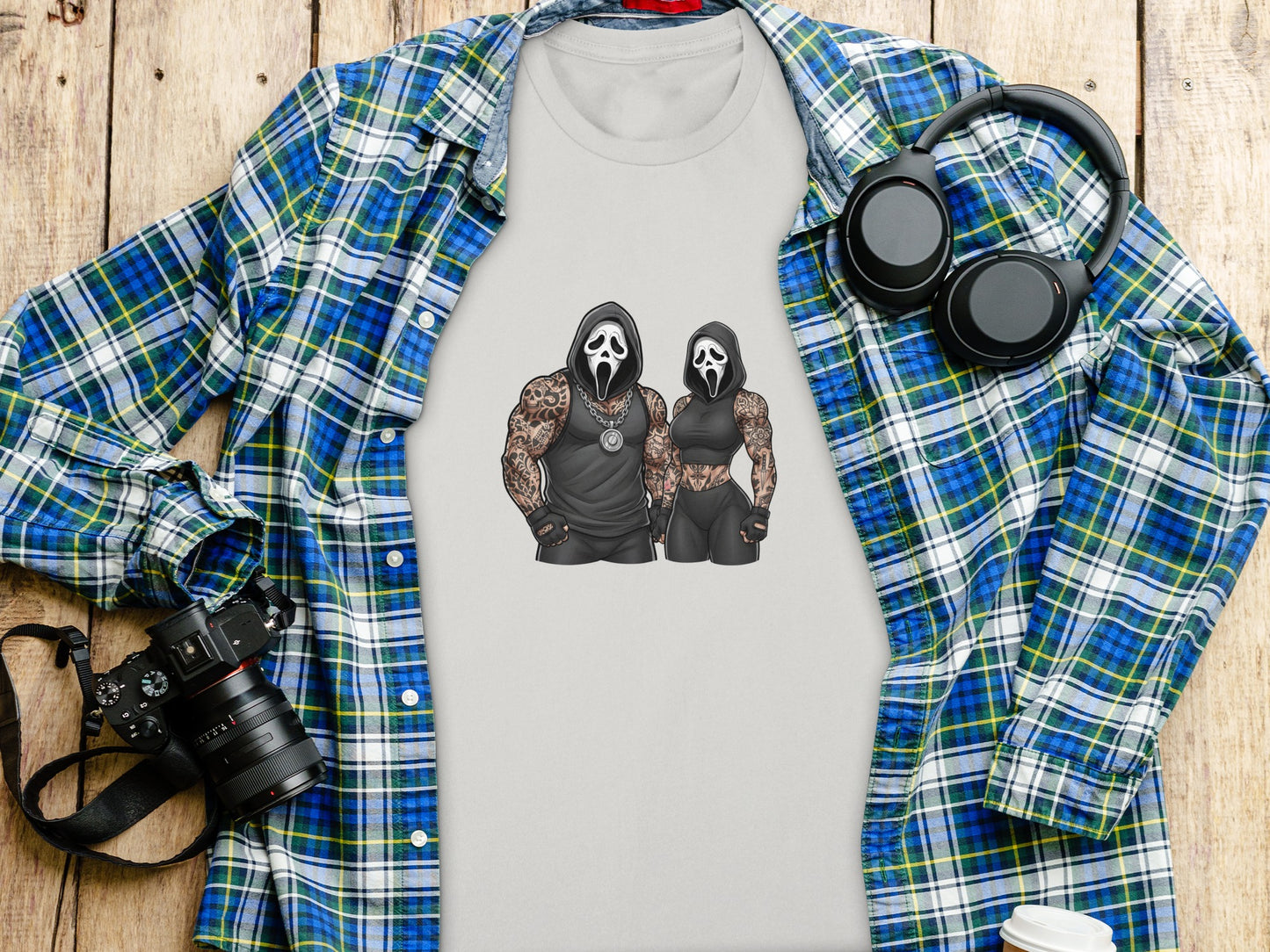 Ghostface couple graphic on a gray t-shirt, flat lay with flannel and headphones.