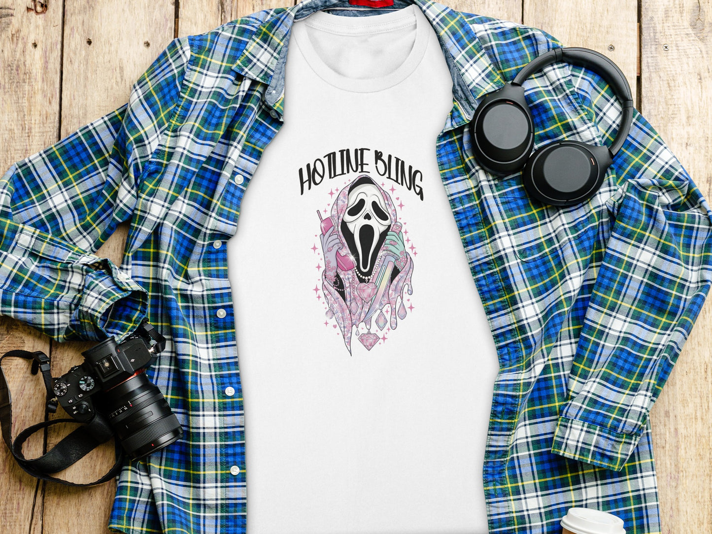 White t-shirt with "Hotline Bling" ghost graphic, laid flat with headphones and camera.