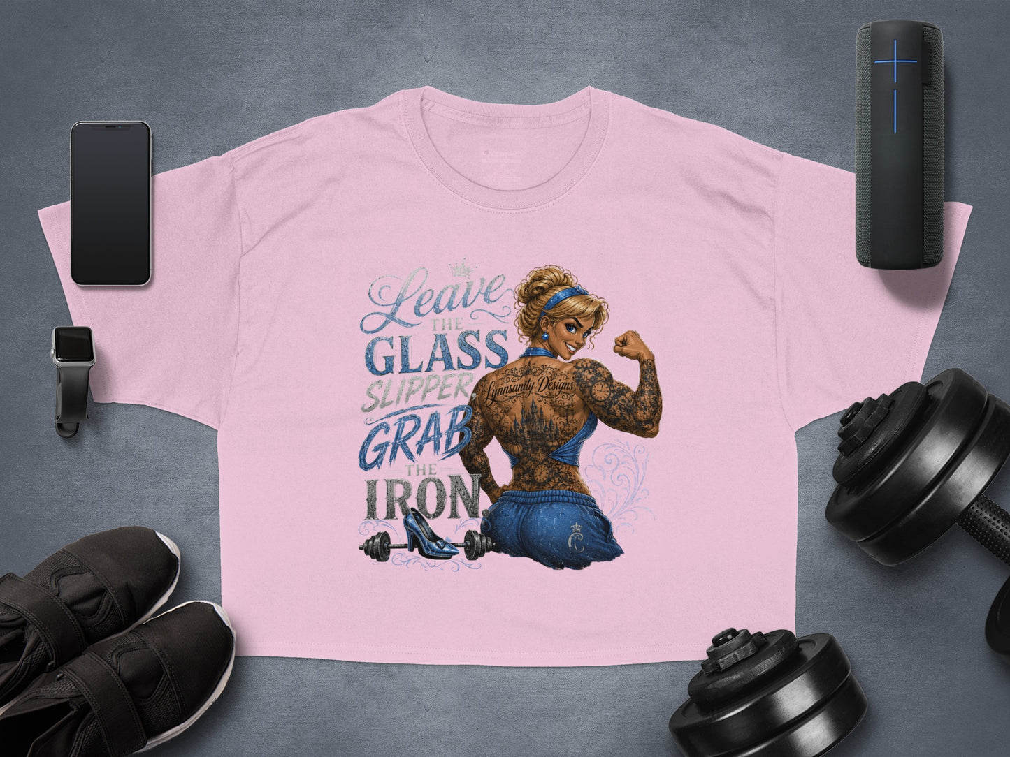 Pink t-shirt with "Leave the glass slipper, grab the iron" and tattooed woman flexing.