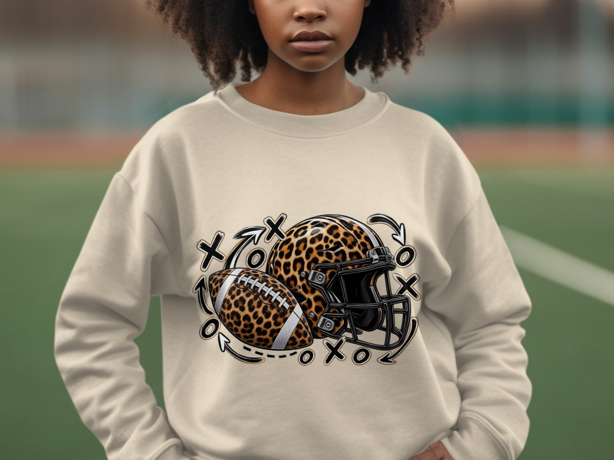 Light tan crewneck sweatshirt with leopard print football, helmet, and tic-tac-toe design.