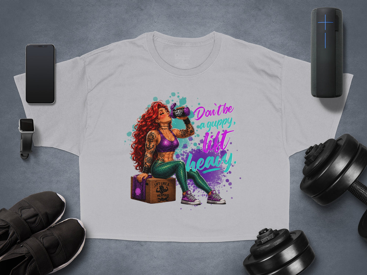 Woman with tattoos and purple hair drinks from a can, text reads "Don't be a guppy, lift like a mermaid".