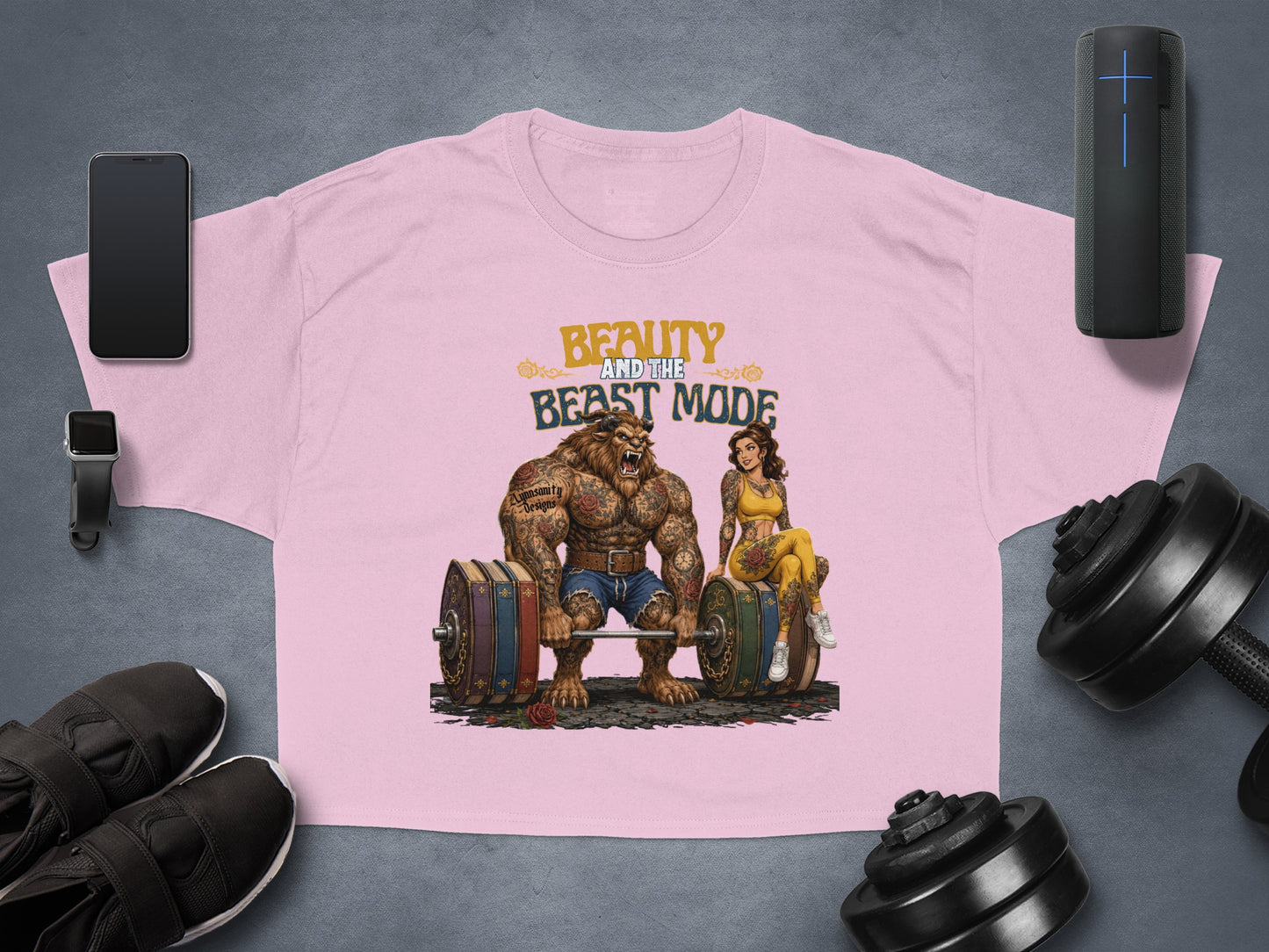 Beauty and the Beast Mode graphic on pink cropped t-shirt with dumbbells and phone.