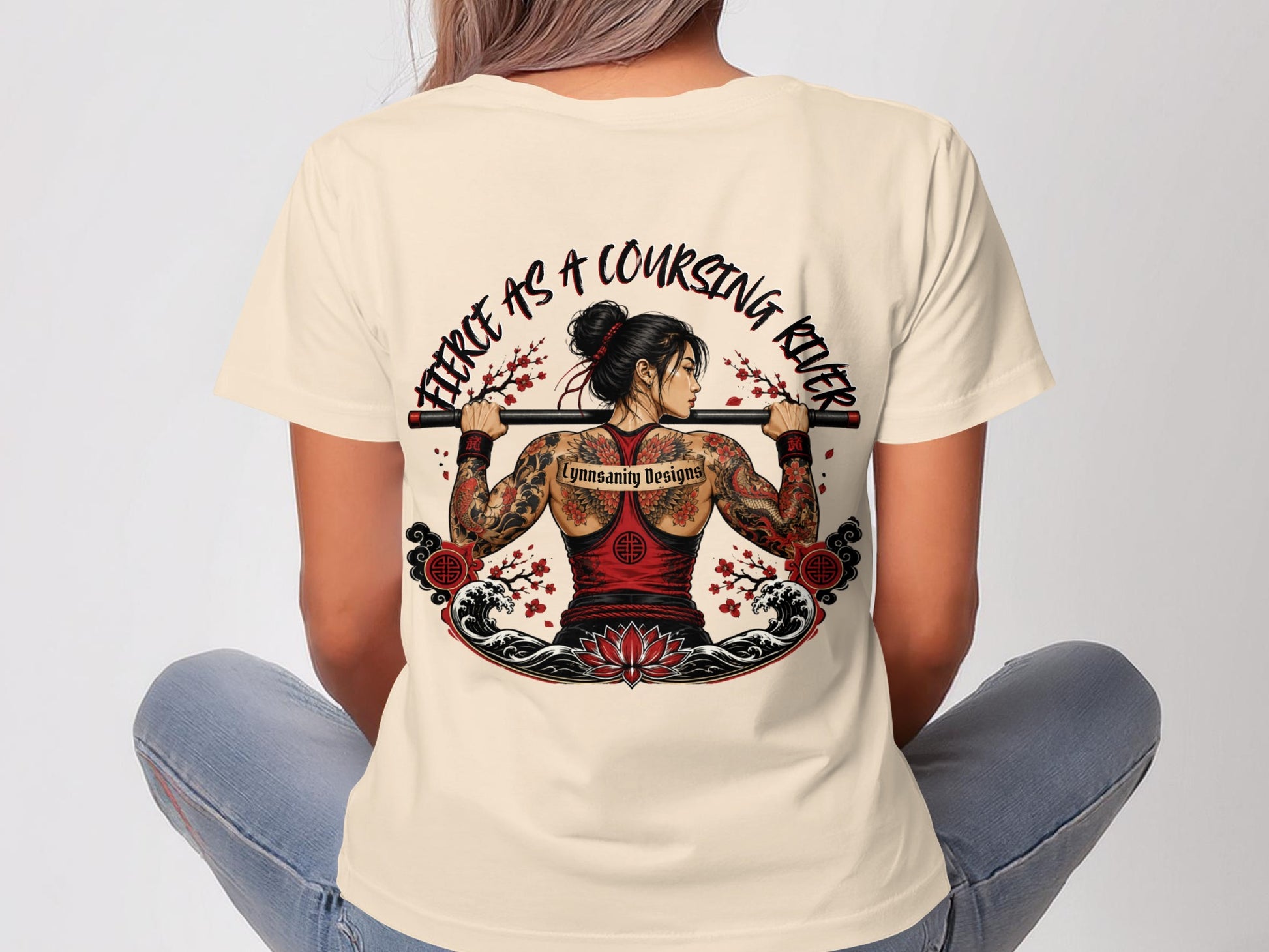Woman with back tattoo, wearing cream t-shirt with fierce river graphic.