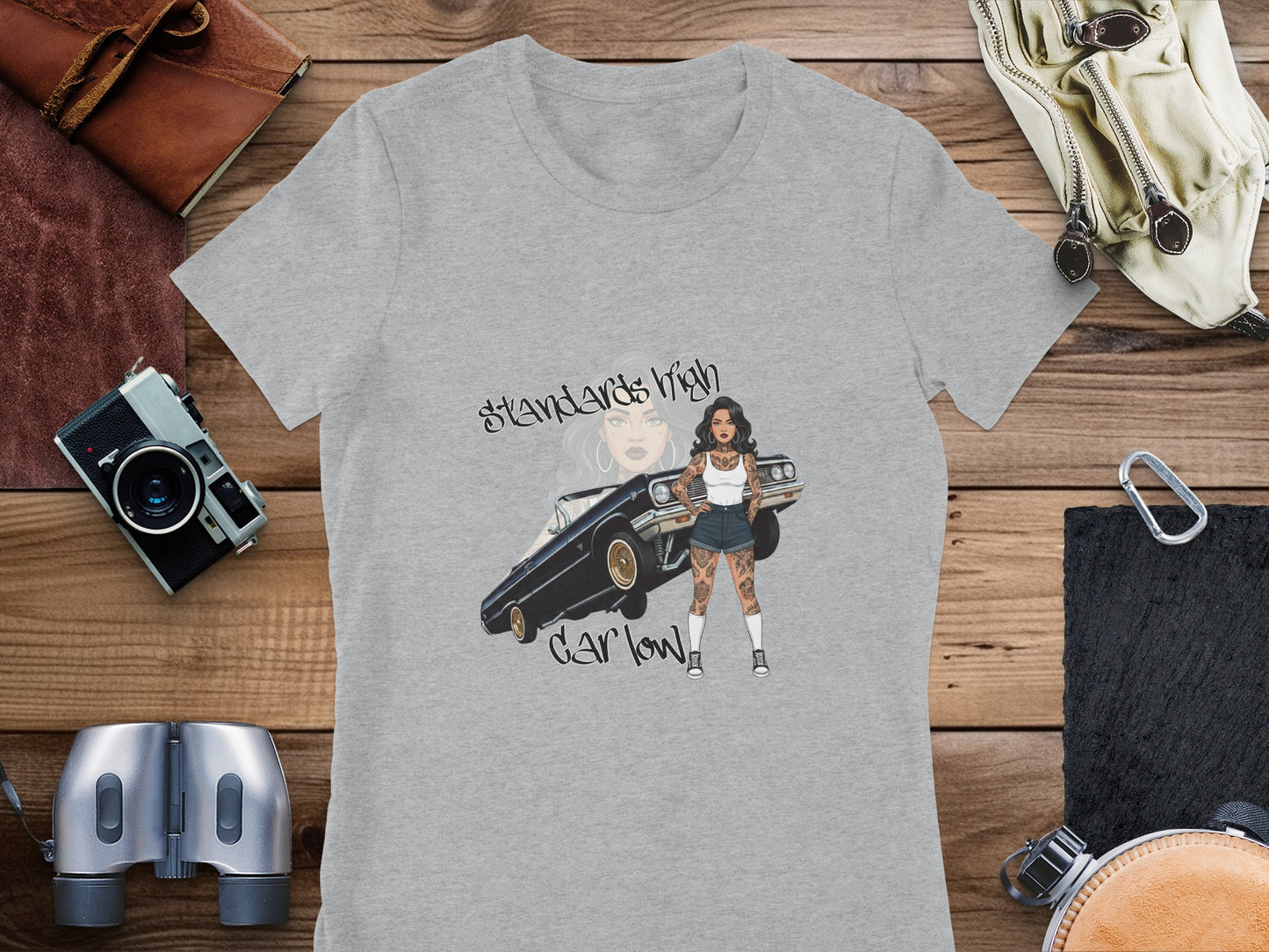 Graphic t-shirt with "Standards High, Car Low" text and woman with tattoo leaning on classic car.
