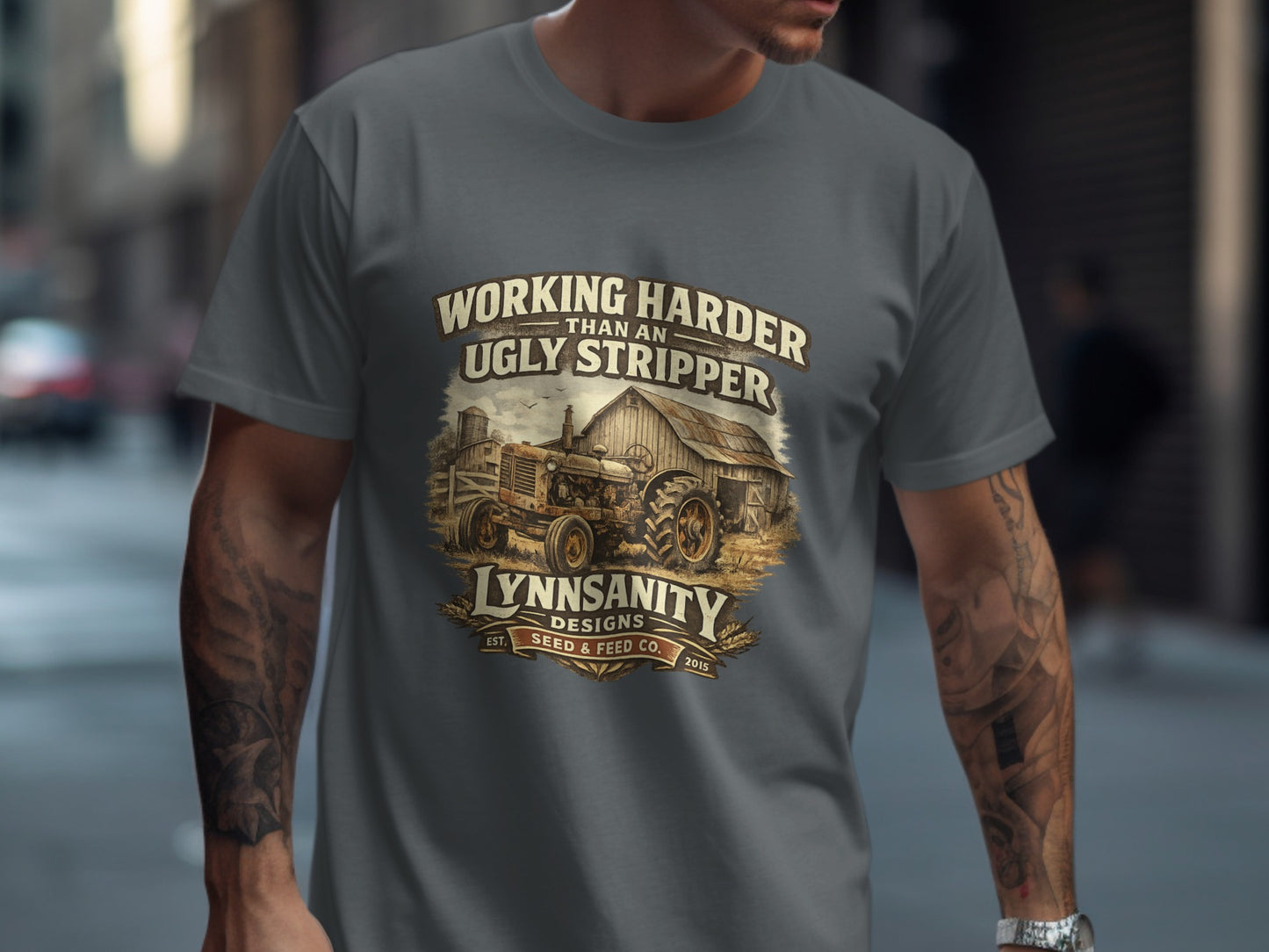 T-shirt with graphic of tractor, barn, and text "Working Harder Than an Ugly Stripper, Lynnsanity Designs Seed & Feed Co."