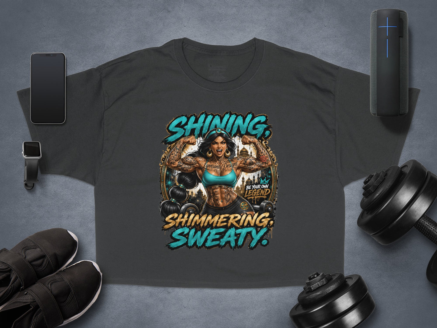 Dark grey t-shirt featuring tattooed woman flexing with "Shining, Sweaty, Be Your Own Legend" text.