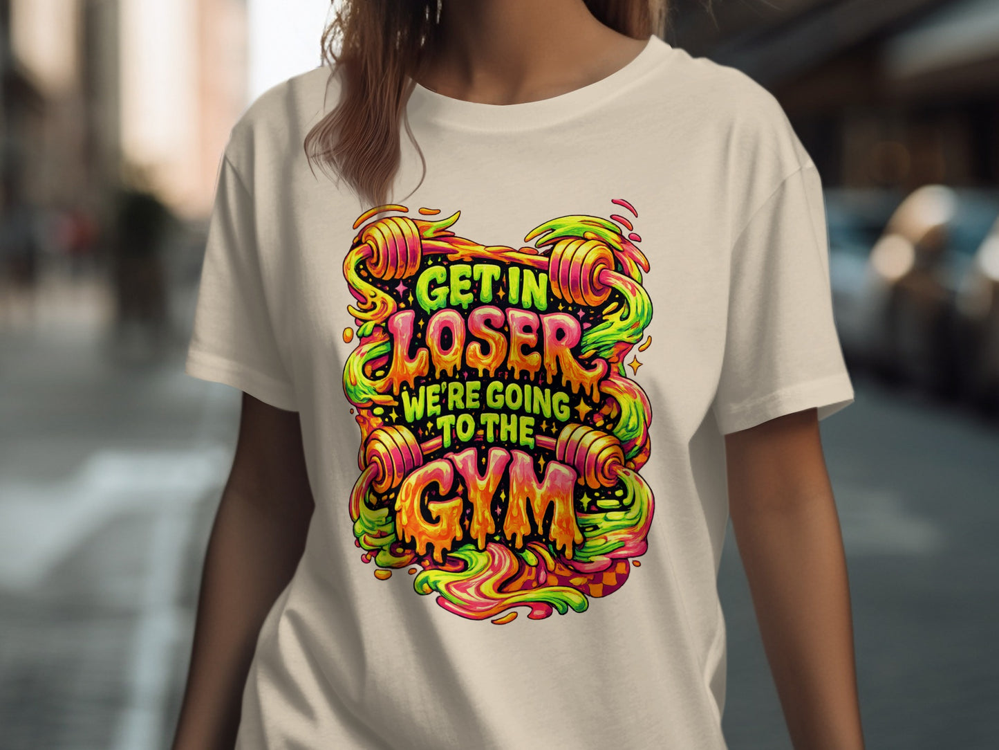 Graphic t-shirt with "Get In Loser We're Going To The Gym" text and colorful barbell design.