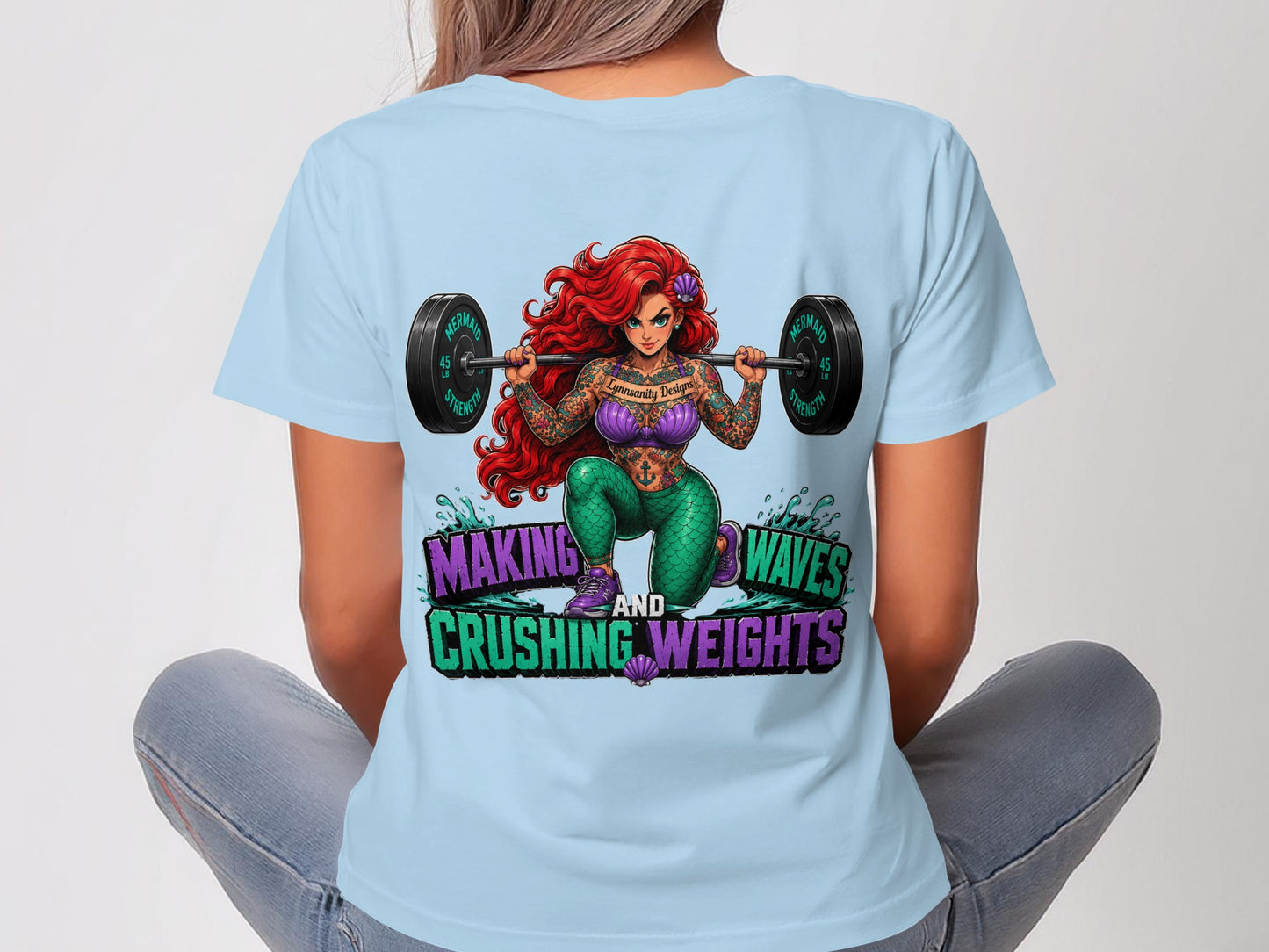 Woman in light blue t-shirt with tattooed Ariel lifting barbell, "Making Waves and Crushing Weights" text.