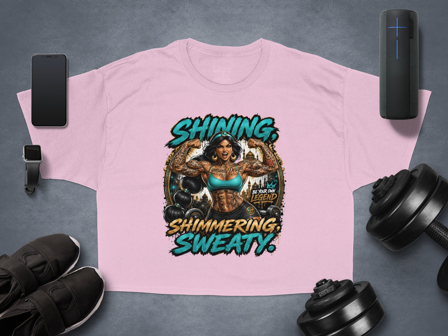 Pink graphic tee with "Shining. Sweaty. Be Your Own Legend." text and Jasmine flexing.