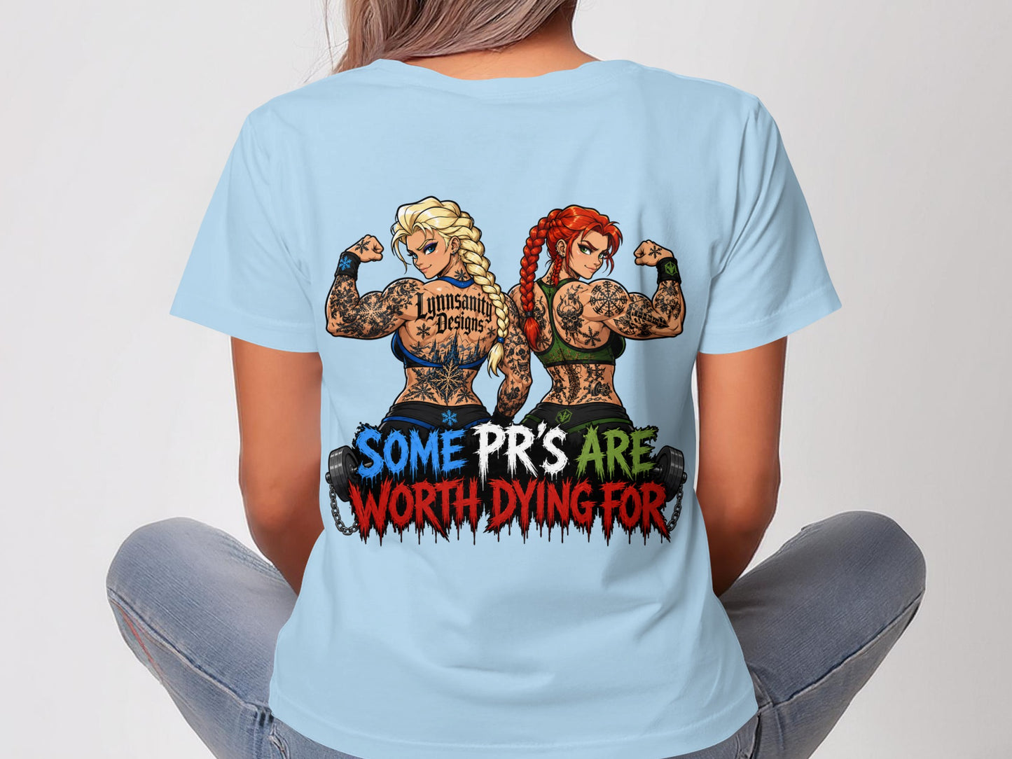 Two tattooed women with braided hair flexing their biceps on a light blue t-shirt.