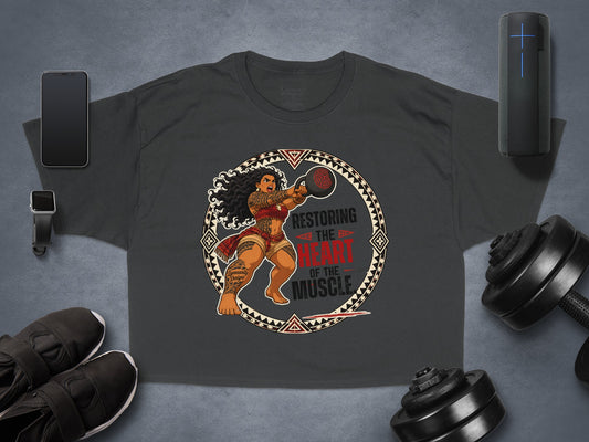 Dark t-shirt with a warrior woman lifting a kettlebell, text "Restoring the Heart of the Muscle."