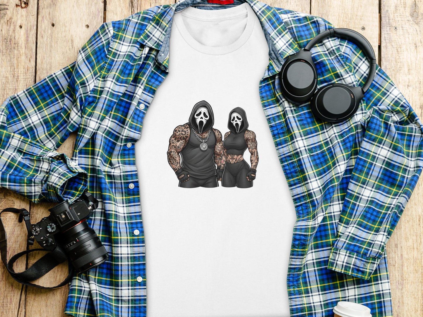 White t-shirt with Ghostface characters, laid on a wooden surface.