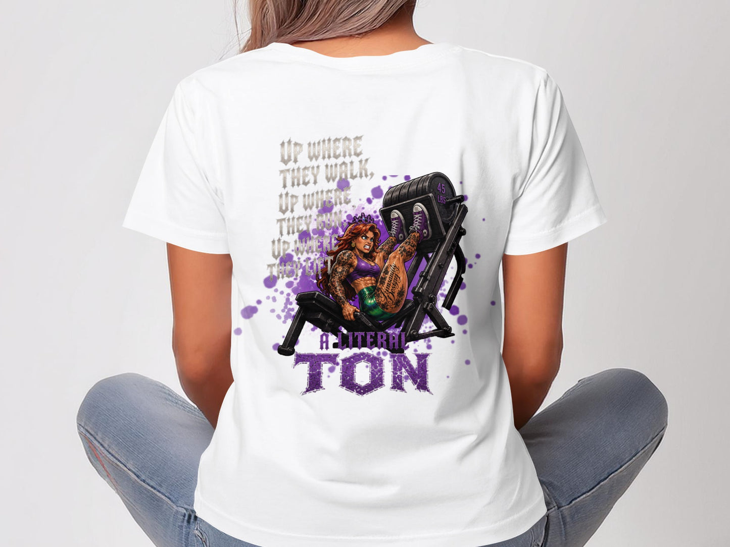 Woman wearing a white t-shirt with tattooed woman on leg press and text.